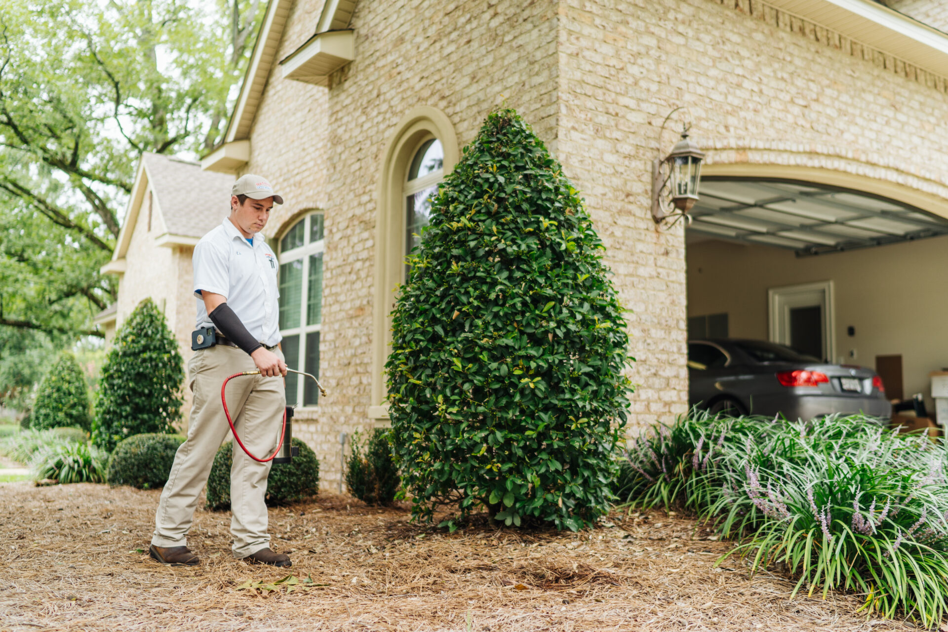 man checking for termites outside of a suburban home