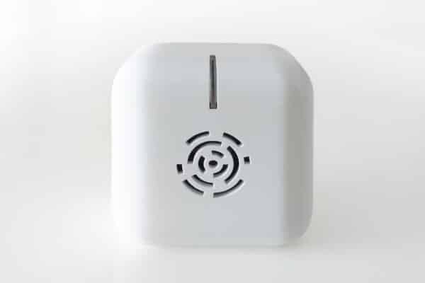 A compact white cube electronics device featuring a circular front vent and single top slot, set against a plain white background.